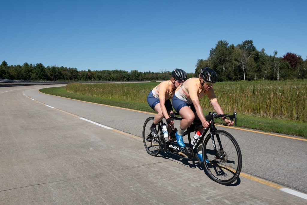 Deux personnes circulant à vélo sur un sentier panoramique par une journée ensoleillée. Two people riding bicycles on a scenic trail on a sunny day.